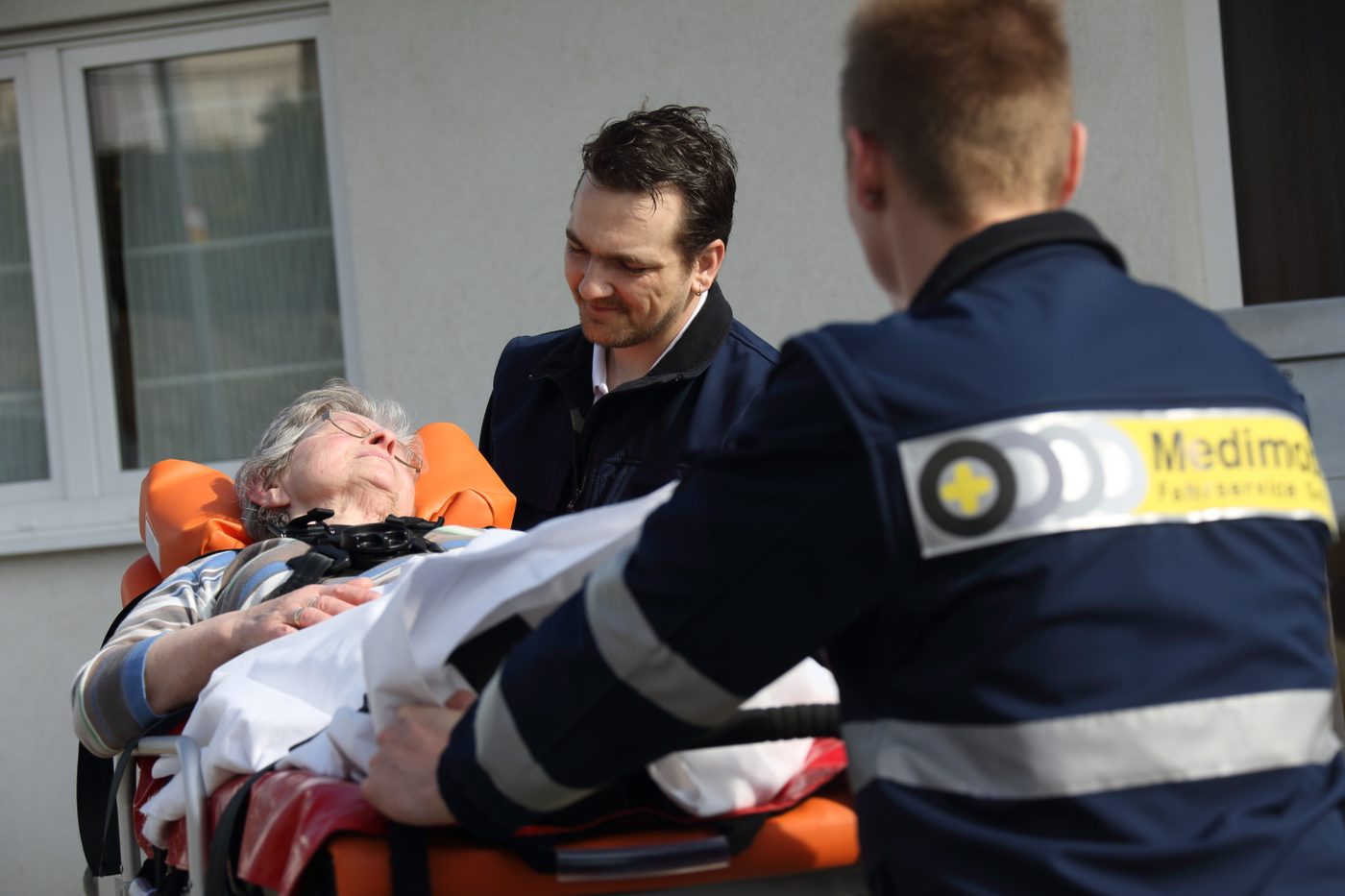 Eine Patientin liegt auf der Krankenfahrtrage und unterhält sich mit einem Medimobil-Mitarbeiter