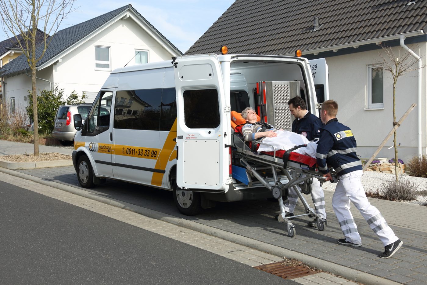 Eine Patientin wird liegend auf der Krankenfahrtrage in ein Medimobil-Krankenfahrzeug geschoben